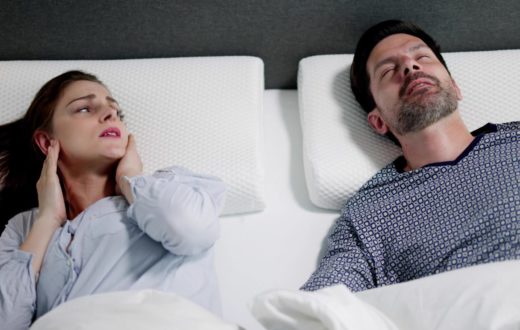 Photo of a woman and man in bed and the woman covering her ears
