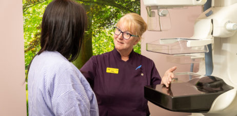 Woman being talked through the process of having a mammogram.