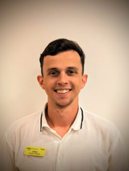 Headshot of a smiling man with short dark hair, wearing a white polo shirt with black trim on the collar.