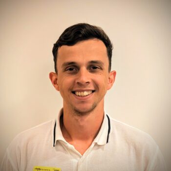 Headshot of a smiling man with short dark hair, wearing a white polo shirt with black trim on the collar.