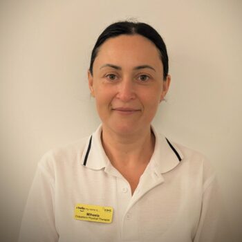 Headshot of a woman with long dark hair, wearing a white polo shirt with black trim and a yellow name tag.