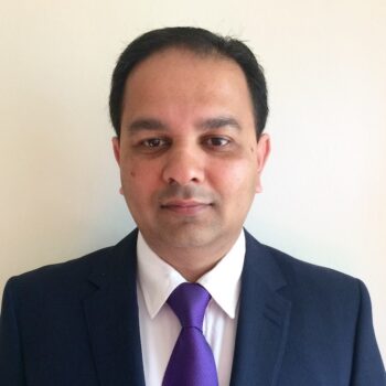 Professional photo of Dr. Vikram Sharma, a Gastroenterologist wearing a navy suit and purple tie against a plain wall.