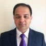 Professional photo of Dr. Vikram Sharma, a Gastroenterologist wearing a navy suit and purple tie against a plain wall.
