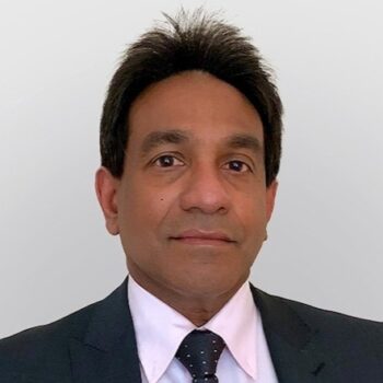 Professional headshot of Dr. Asankha Ranasinghe, wearing a dark suit, white shirt, and patterned tie against a wall.