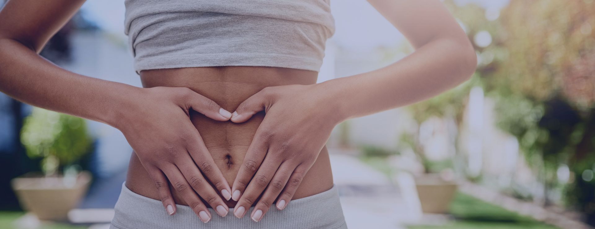 A person’s hands forming a heart shape over their stomach, symbolizing digestive health and well-being.